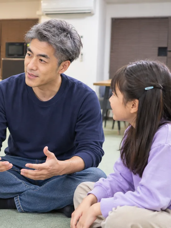 床に座って輪になり話すスタッフと子どもたち